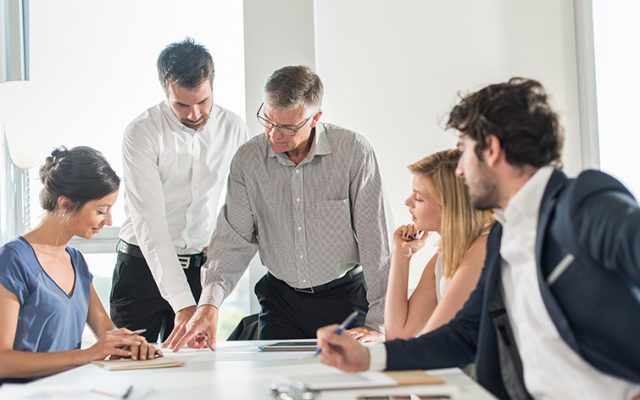 Solicitors and clients meeting around a table during an attended exchange.