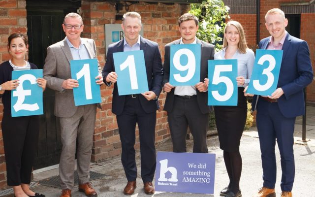 Six people stood in a row holding cards showing the total raised during the Helen's Trust Free Wills Month